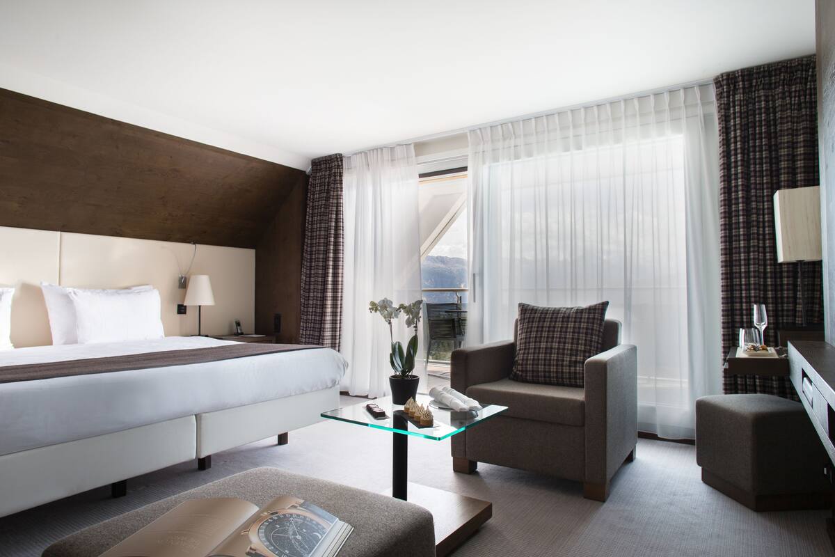 Una habitación de hotel moderna con una cama, una mesita de vidrio, un sofá y un escritorio.