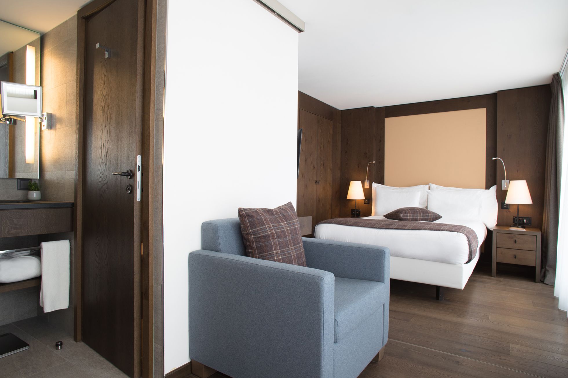Una camera d'albergo con un letto, comodini, una sedia, una scrivania e uno specchio.
