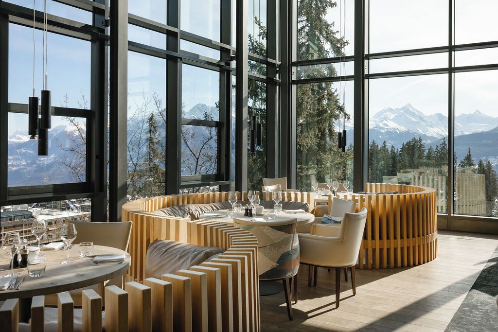 A modern dining area with a view of mountains through large windows.