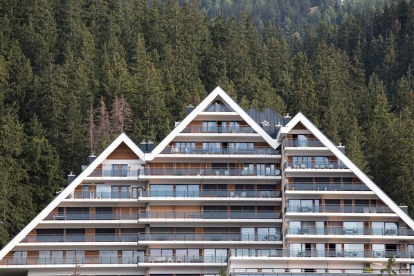 Un hotel de varios pisos con un diseño de techo triangular, ventanas grandes y balcones.