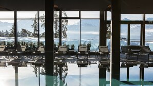 Un área de piscina con sillas y vistas a montañas nevadas.