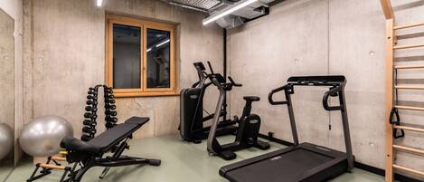 Un gimnasio con equipo de ejercicio, una ventana y una escalera de madera.