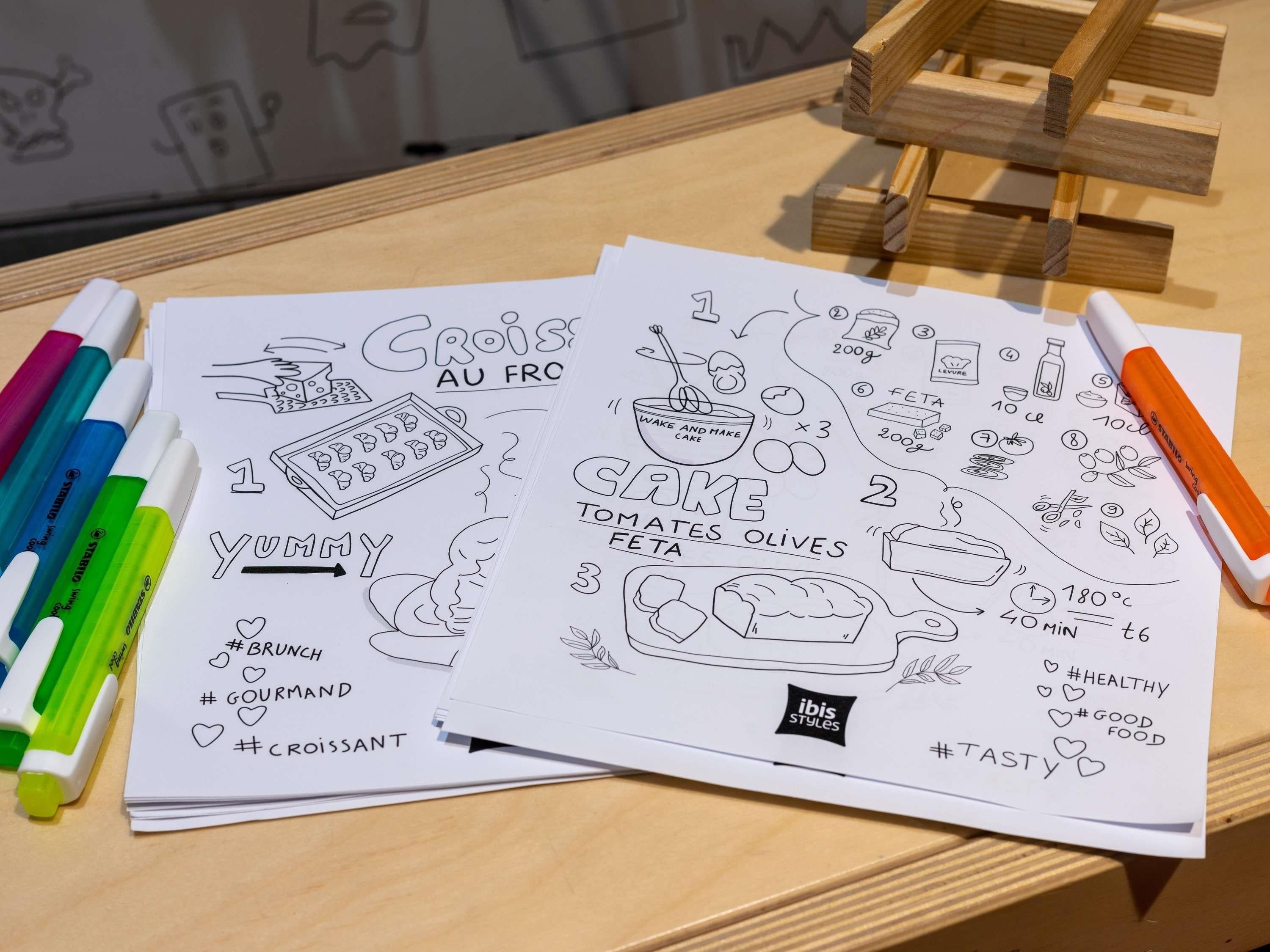 A table with sketchbooks, markers, and a wooden stand.