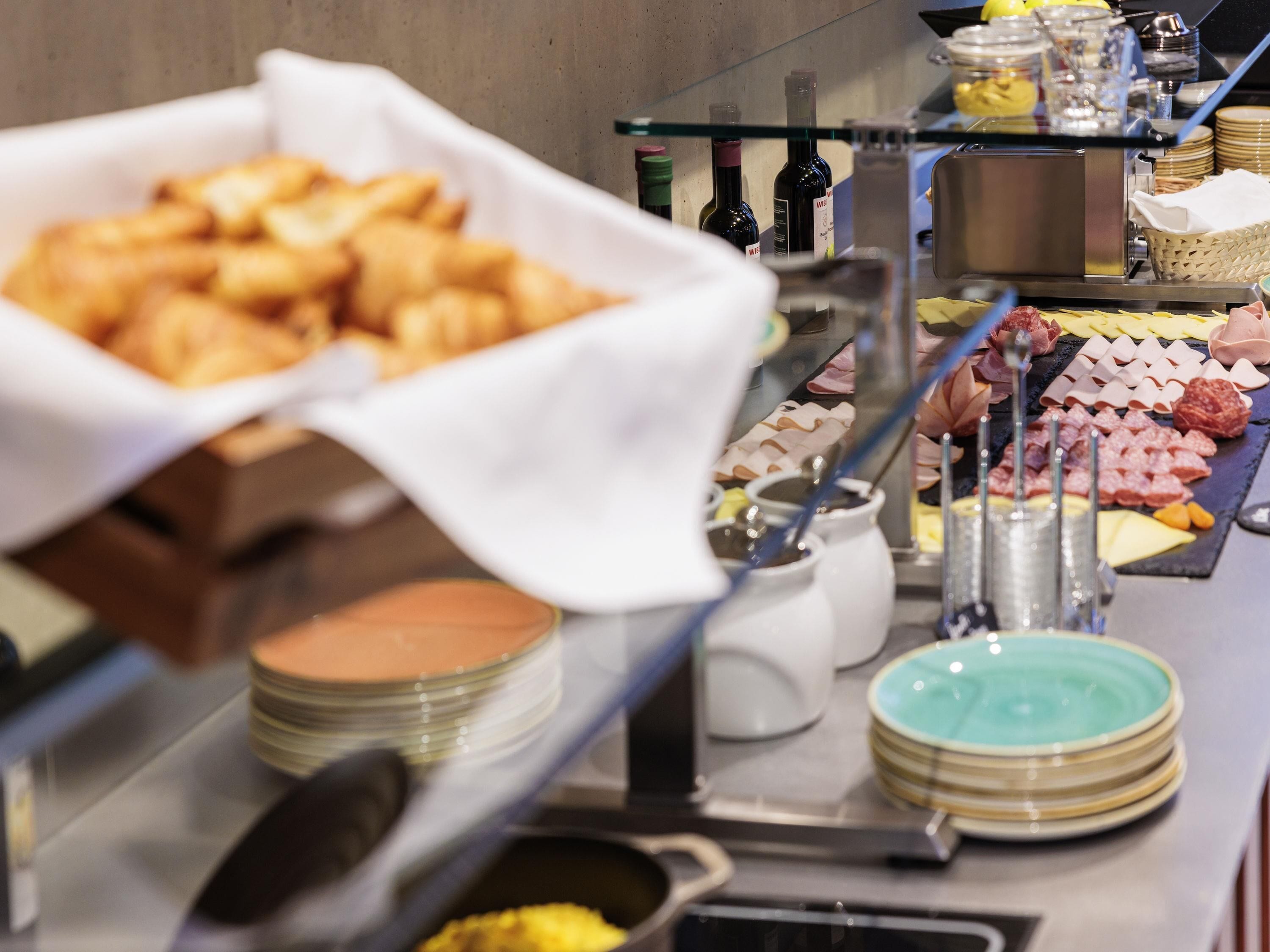 Un buffet proposant une variété de plats, notamment des pâtisseries, des fromages et des viandes.