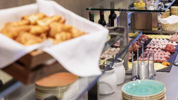Un buffet proposant une variété de plats, notamment des pâtisseries, des fromages et des viandes.