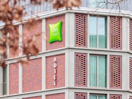 Un hotel con diseño moderno, que destaca un cartel grande de 'ibis Styles' y un cartel que dice 'HOTEL' en la fachada.