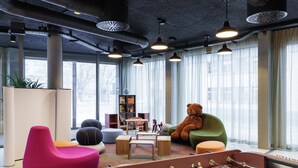 A modern indoor space with a foosball table, colorful seating, and large windows. - ibis Styles Bern City (Bern)