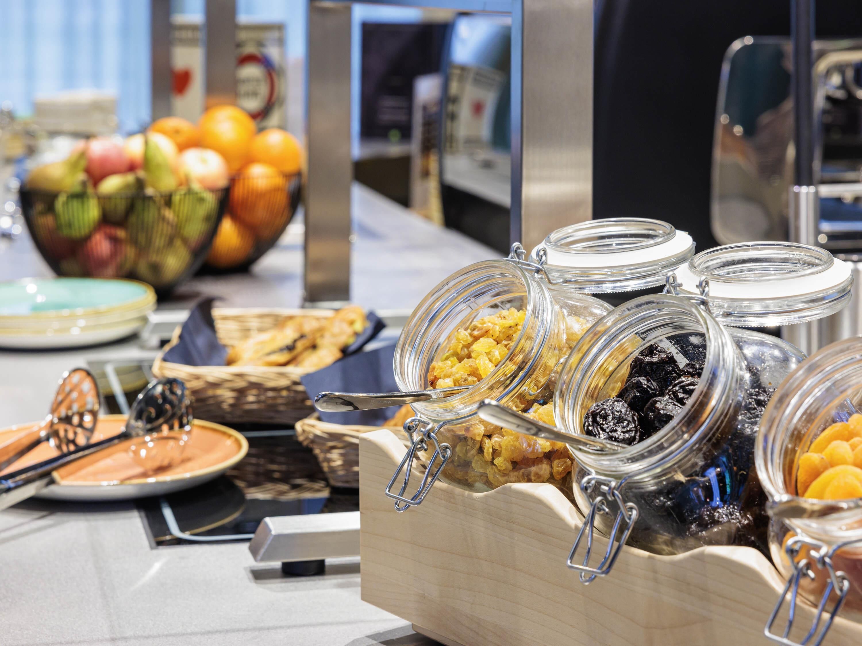 A buffet with various food items, including fruits, cereals, and pastries.