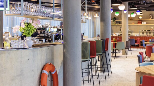 A bar area with a counter, glasses, and a life preserver. - ibis Styles Bern City (Bern)