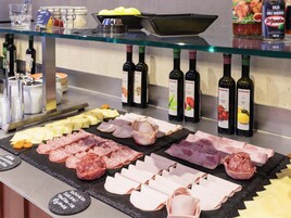 A buffet with various meats, cheeses, and condiments.