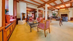 A spacious lobby with high ceilings, wooden beams, and a central seating area with chairs and a table. - Hotel Regina Wengen (Lauterbrunnen)