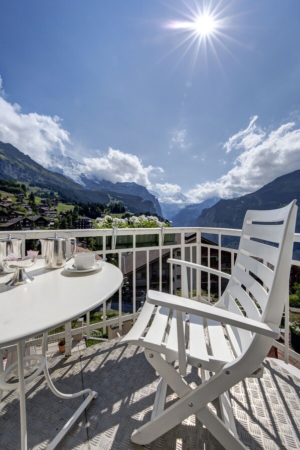 A terrace with a white table and chair, overlooking a mountainous landscape.