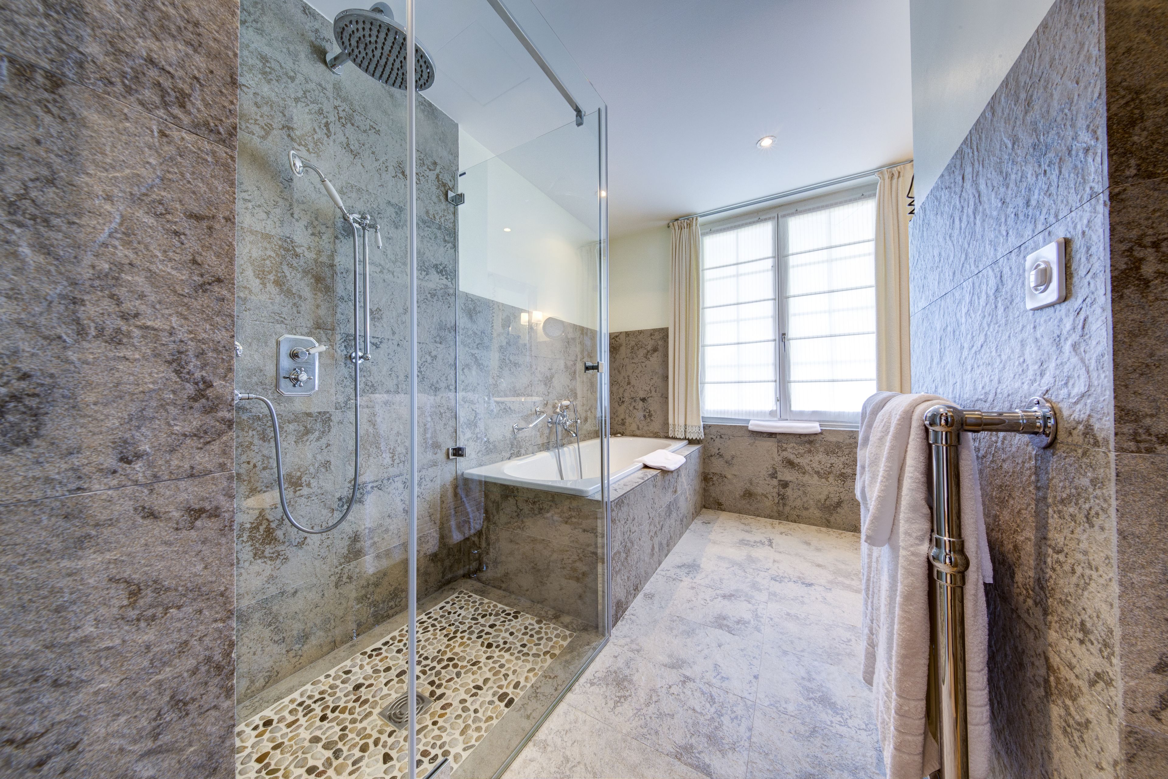 Un baño moderno con ducha de vidrio, bañera y zona de ducha a ras de suelo.
