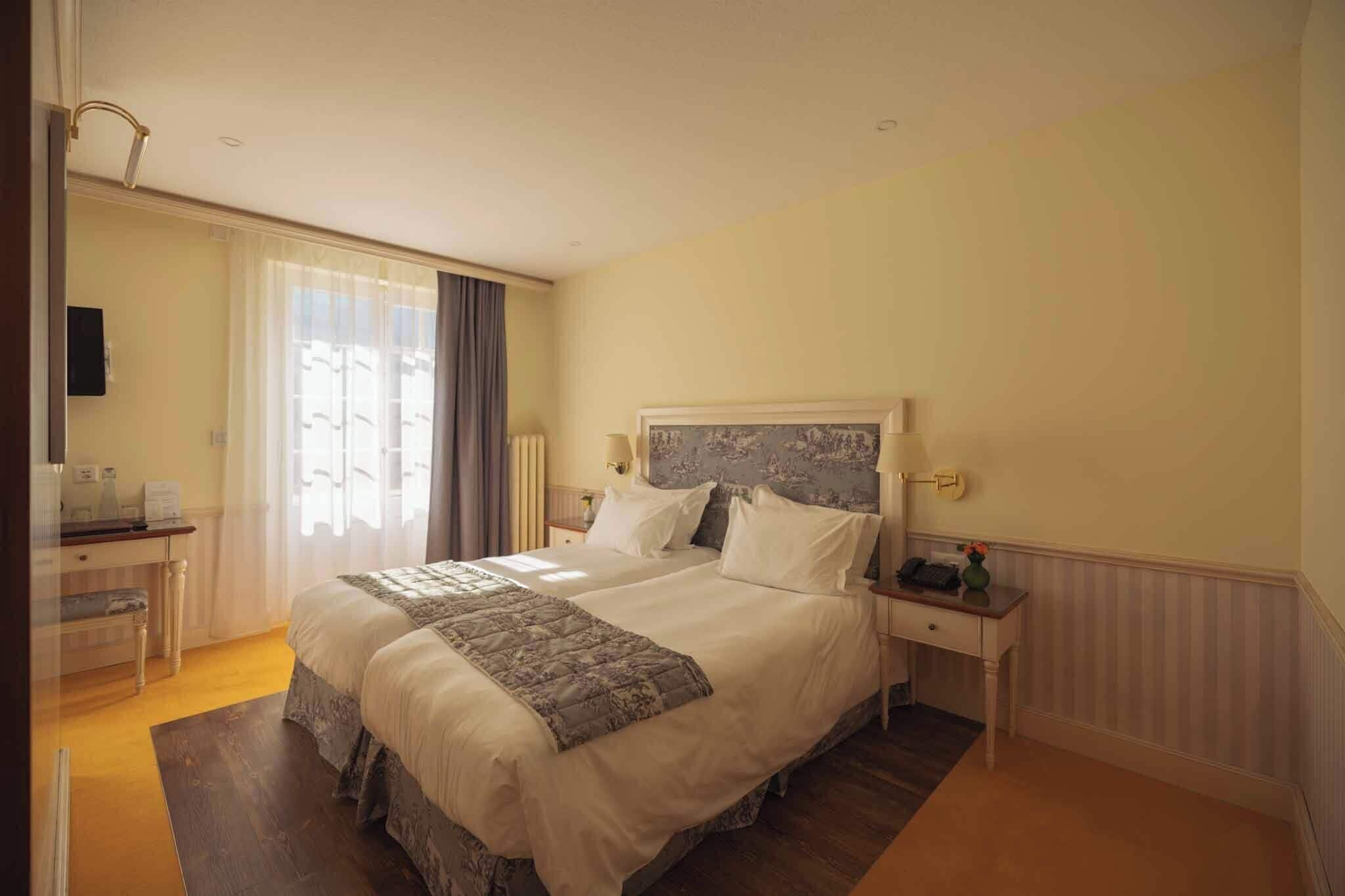 A double bed with a headboard, bedside tables, a desk, and a chair.