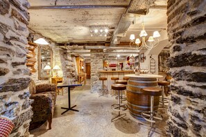 Ein rustikaler Innenraum mit Steinwänden, Holzbarhocker und einer Bar.