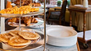 A breakfast buffet with waffles, croissants, and pastries on a metal stand. - Hotel Regina Wengen (Lauterbrunnen)