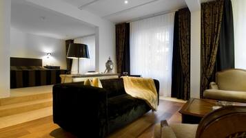 Una sala de estar moderna con un sofá negro, un sillón color beige y una mesa de centro de madera.