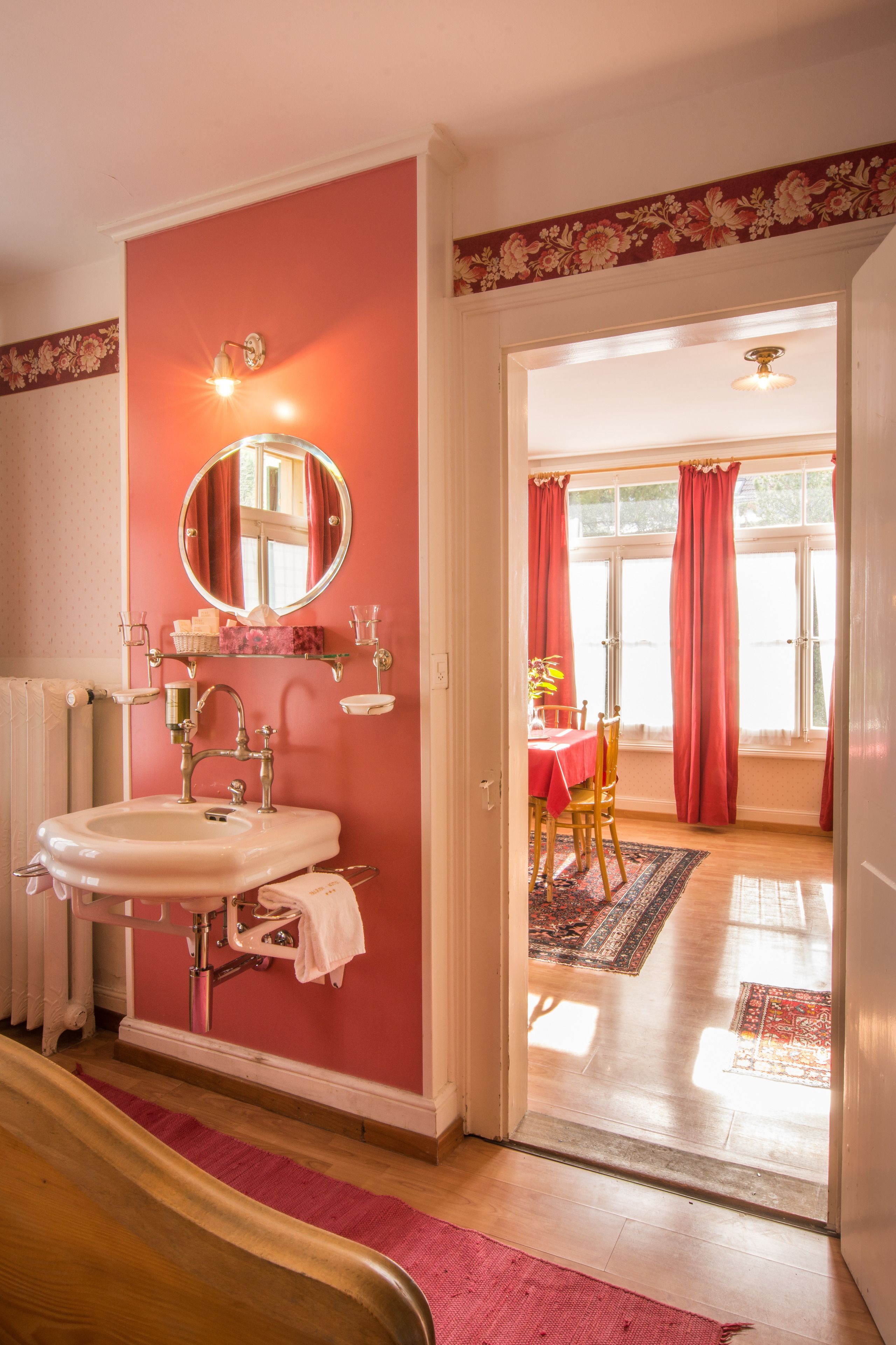 A bathroom with a sink, mirror, and a window with curtains.
