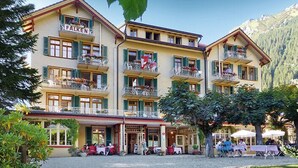A hotel with multiple balconies, outdoor seating, and a mountainous backdrop. - Hotel Falken (Lauterbrunnen)