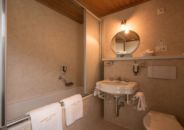 Un baño con lavamanos, espejo e inodoro.