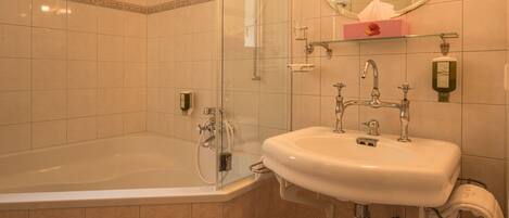 A bathroom with a bathtub, a sink, and a glass-enclosed shower.