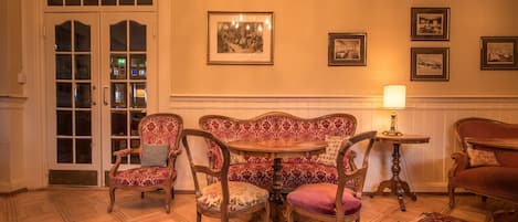A room with a wooden table and four chairs, a patterned rug, and a door with glass panels.