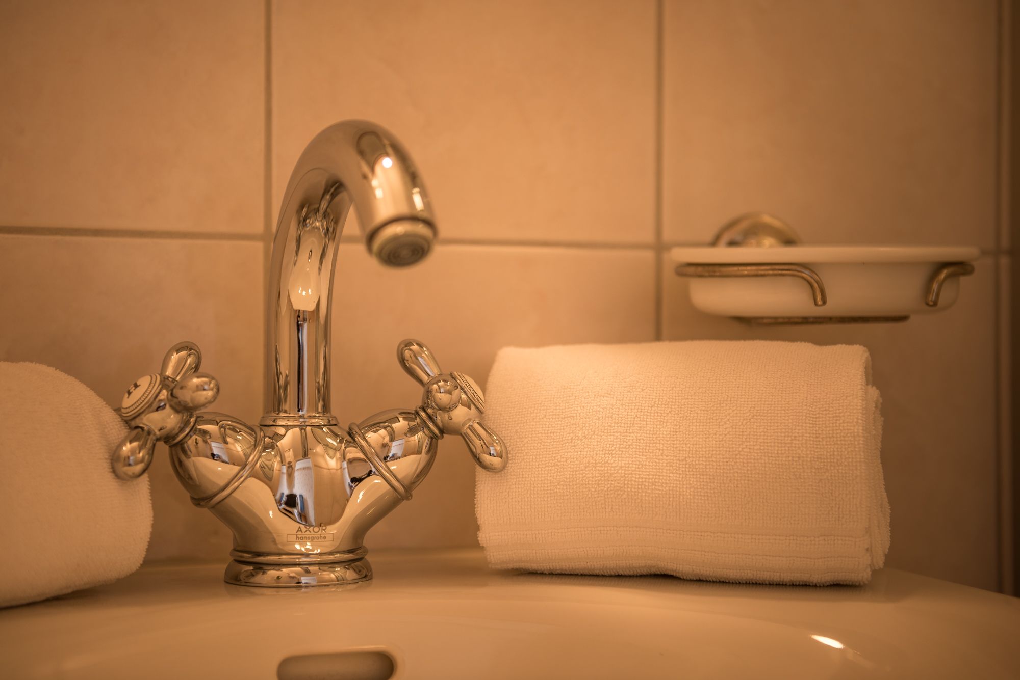 Un lavamanos de baño con grifo cromado, una toalla blanca y un lavabo pequeño de color blanco.