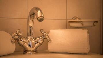 Un lavamanos de baño con grifo cromado, una toalla blanca y un lavabo pequeño de color blanco.