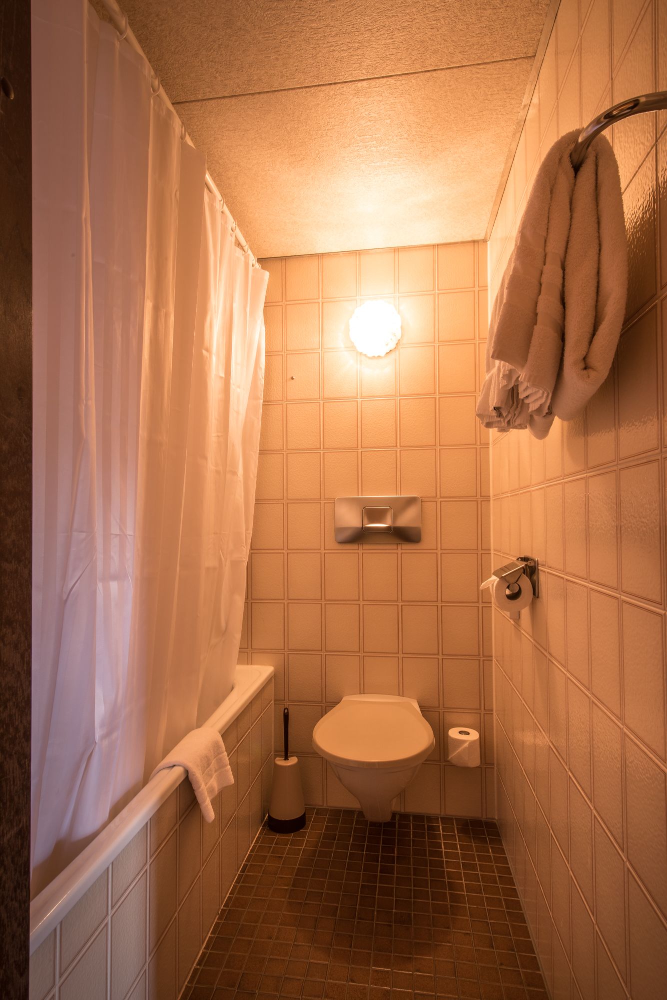 Ein kleines Badezimmer mit Fliesen, einer Toilette, einem Händetrockner und einem Handtuchhalter.