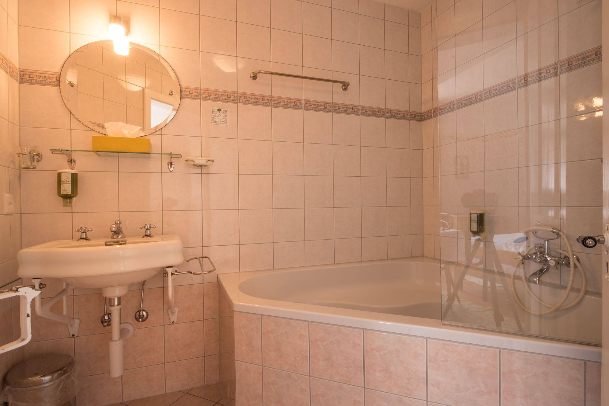 A bathroom with a sink, mirror, and bathtub.