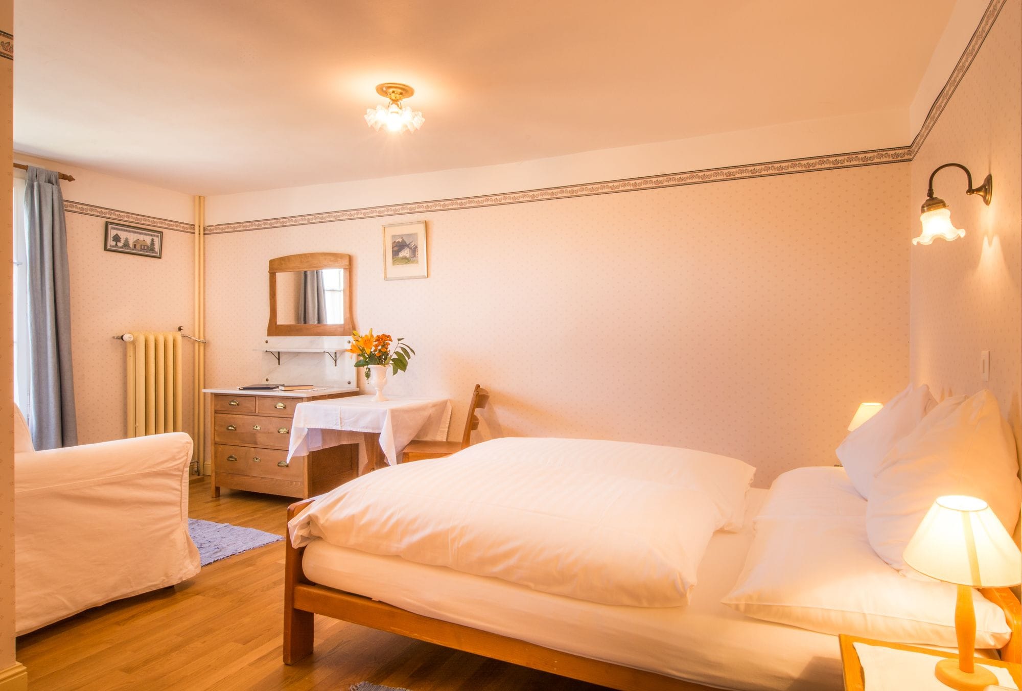Une chambre à coucher comprenant un lit, un bureau, une chaise, une commode et une table de chevet avec une lampe.