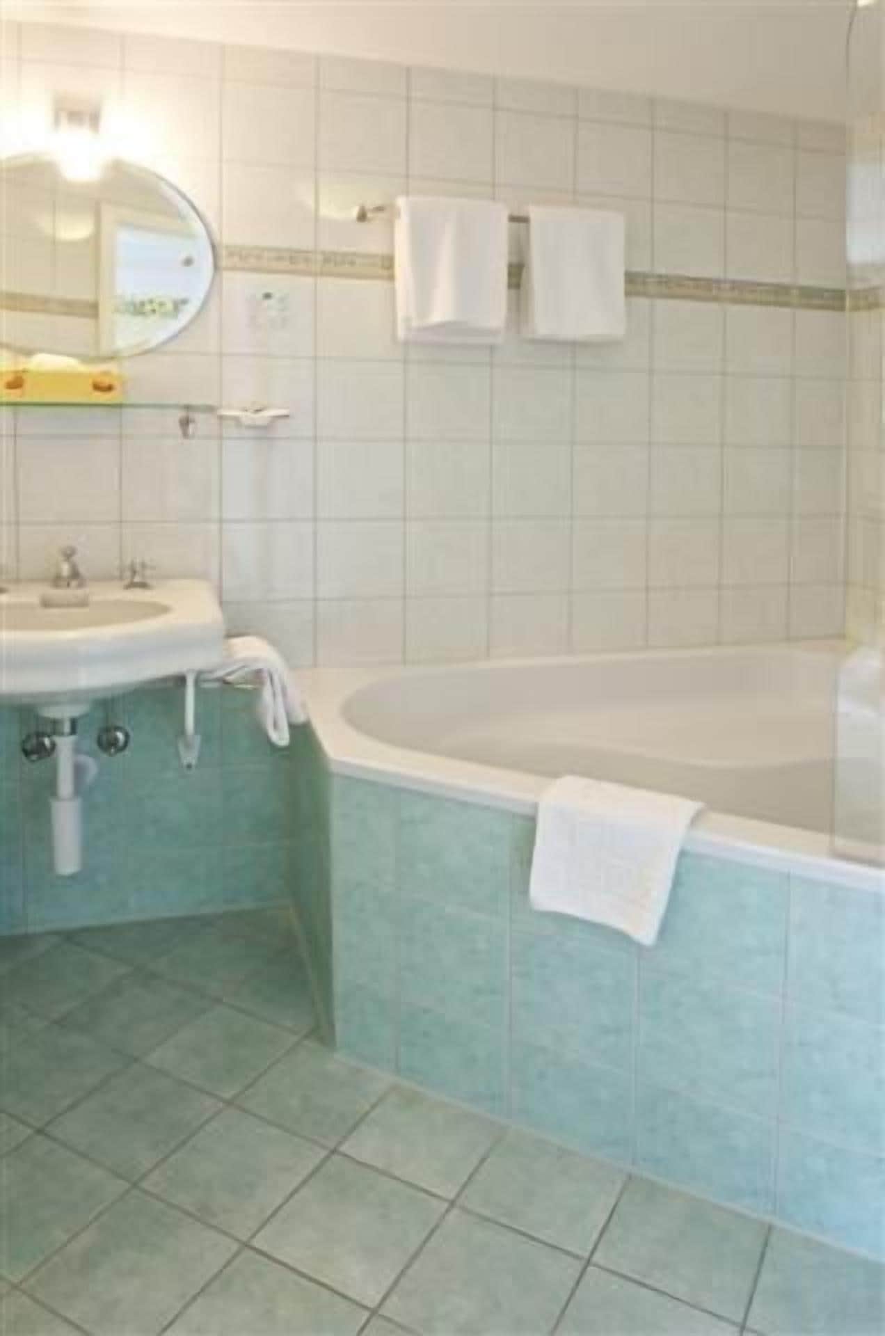 A bathroom with a sink, mirror, and bathtub.