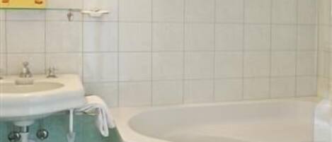 A bathroom with a sink, mirror, and bathtub.