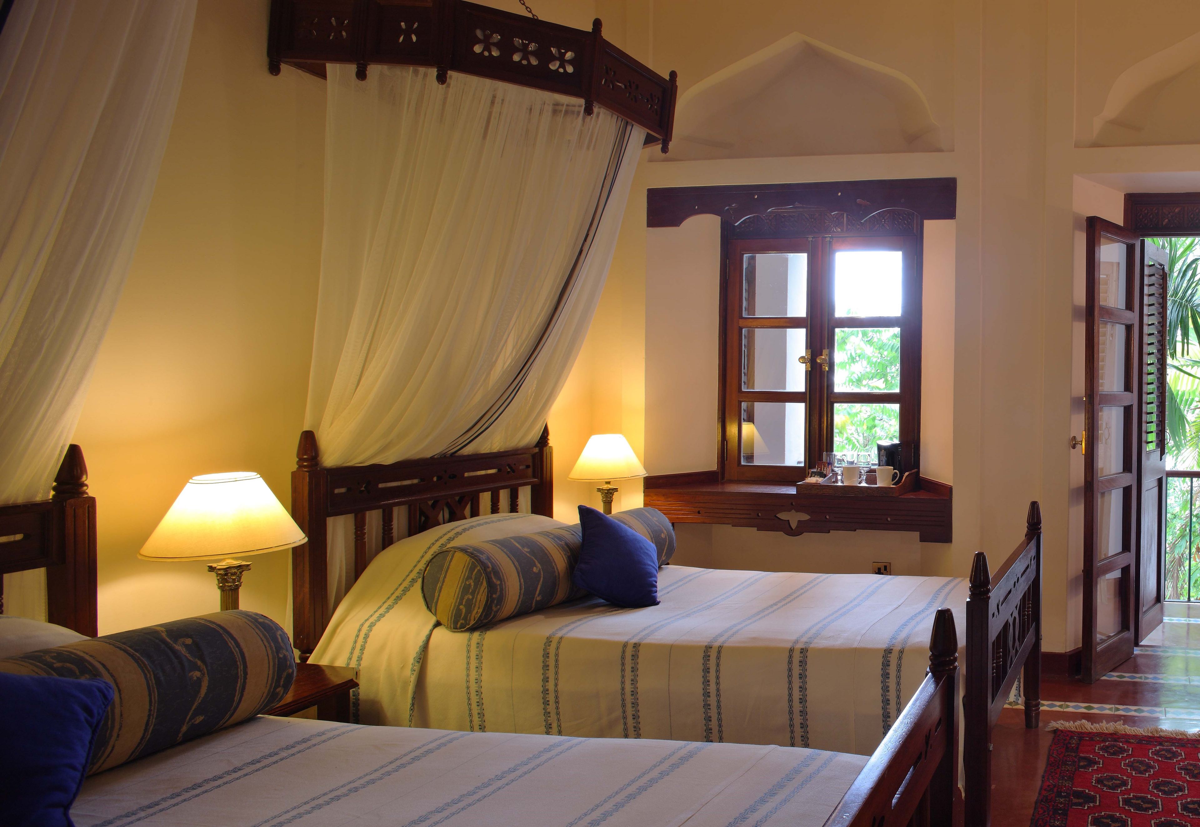 Une chambre avec deux lits, une fenêtre donnant sur un beau paysage et une table de chevet avec une lampe.