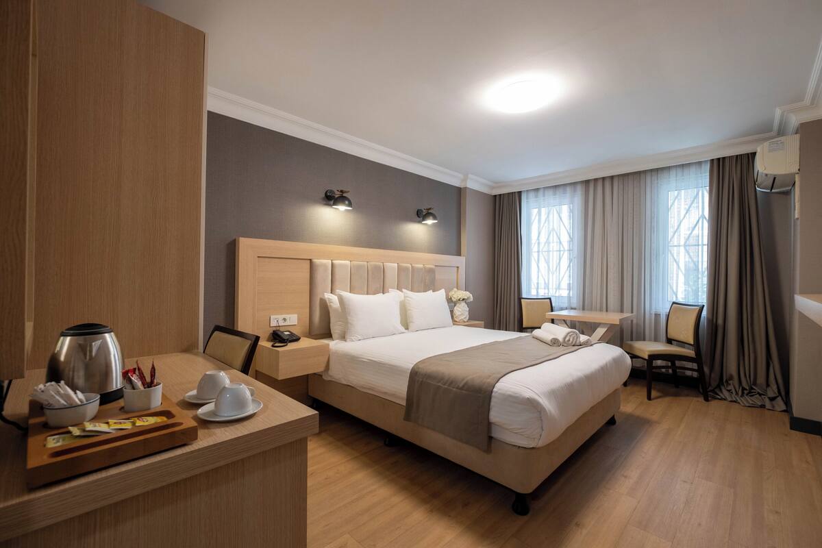 A hotel room with a large bed, bedside tables, a desk, and a chair.