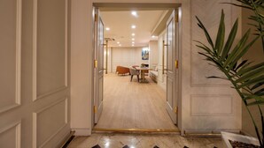 A hallway leading to a dining area with a table and chairs, a sofa, and a plant. - Berr Hotel (Istanbul)