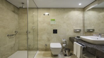 Un bagno moderno con doccia vetro, servizi igienici, lavandino e cestino.
