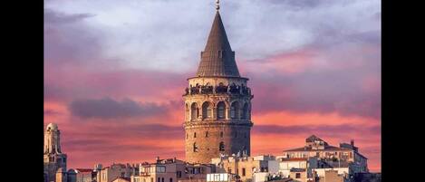 A historic tower with a conical roof, surrounded by a cityscape with various buildings.