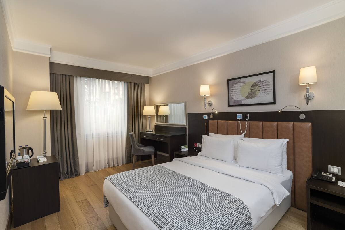A hotel room with a bed, desk, chair, and a television.