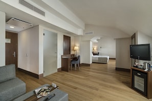 A hotel room with a wooden floor, a desk with a chair, a bed, a TV, and a small kitchenette. - Holiday Inn Istanbul - Old City by IHG (Istanbul)