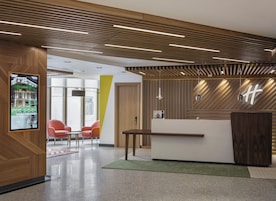 A reception area with a wooden reception desk, a digital display, and a reception counter.
