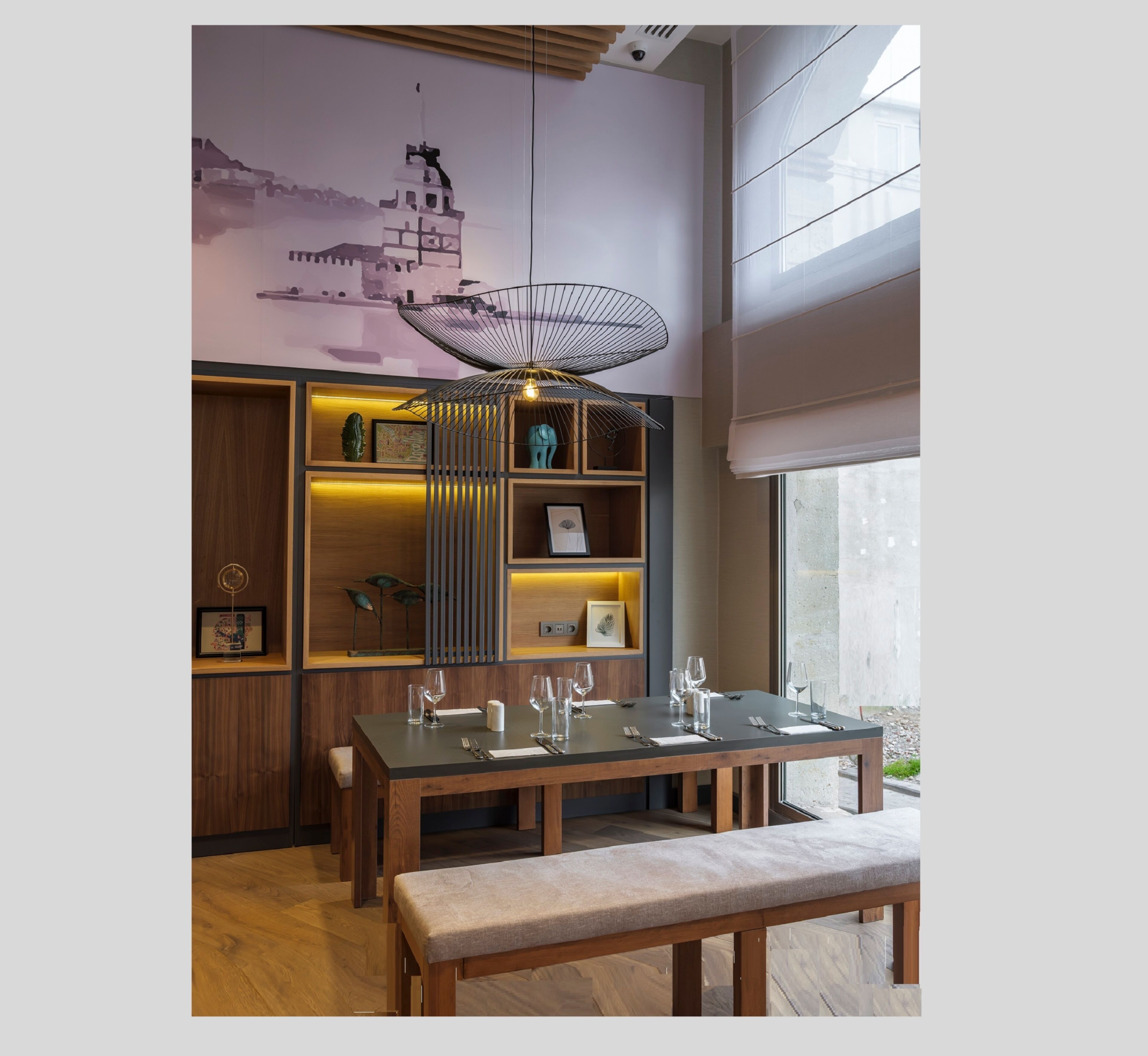 Un moderno comedor con una mesa de madera dispuesta para cuatro, un banco y una lámpara de techo original.