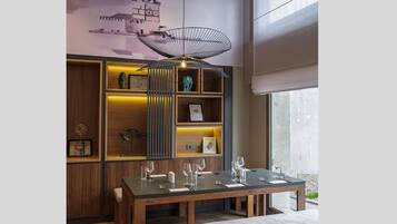 Un moderno comedor con una mesa de madera dispuesta para cuatro, un banco y una lámpara de techo original.