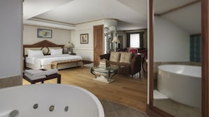 A hotel room with a large bed, a sitting area with a sofa and armchairs, a dining table, and a large bathtub. - Holiday Inn Istanbul - Old City by IHG (Istanbul)