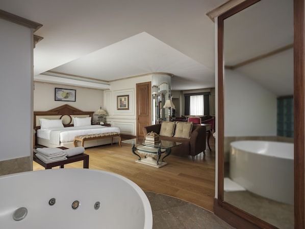 A hotel room with a large bed, a sitting area with a sofa and armchairs, a dining table, and a large bathtub. - Holiday Inn Istanbul - Old City by IHG (Istanbul)
