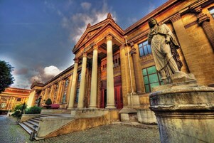 Un edificio clásico con columnas y una estatua al frente.
