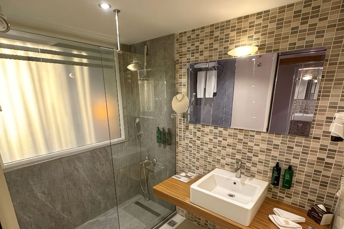 A modern bathroom with a glass-enclosed shower, a double sink vanity, and a tiled backsplash.