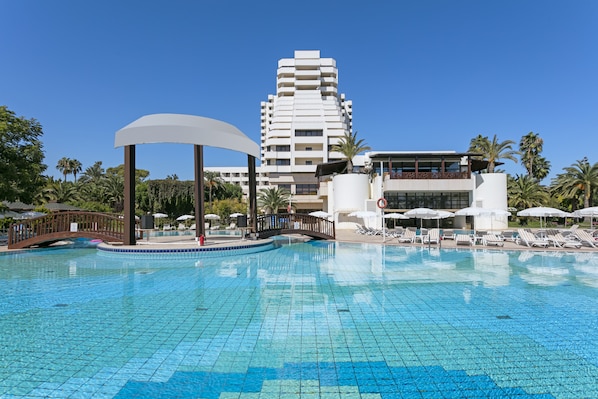 Una piscina al aire libre, sombrillas, tumbonas