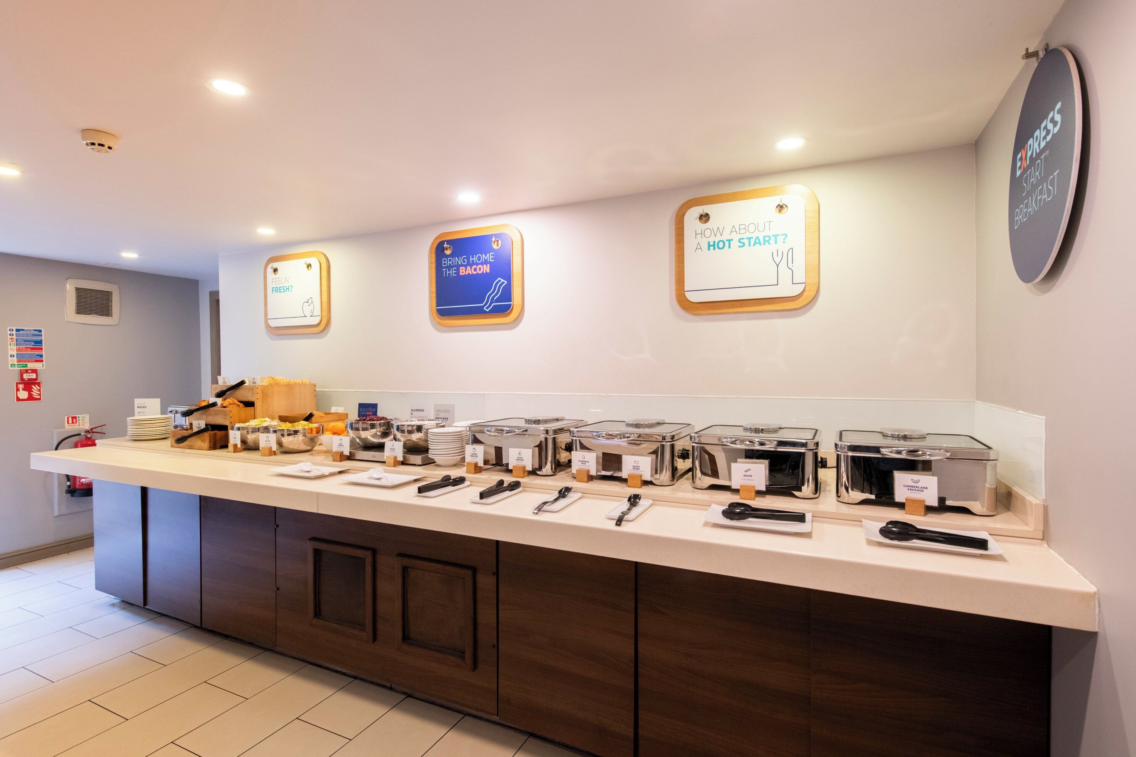 A breakfast buffet area with various food stations and utensils.