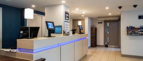 A reception area with a counter, computers, and a blue-lit desk.